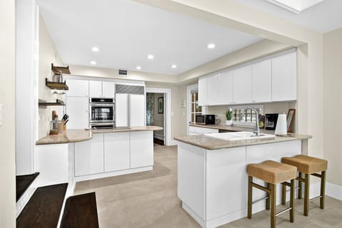 Your spacious modern kitchen features sleek white cabinets, granite countertops, and premium stainless appliances perfect for creating memorable meals during your stay.
