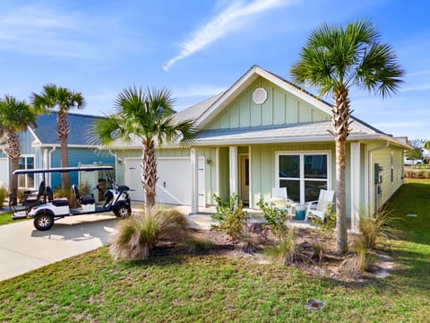 Charming coastal cottage with tropical palm landscaping and convenient golf cart parking in a peaceful residential setting.