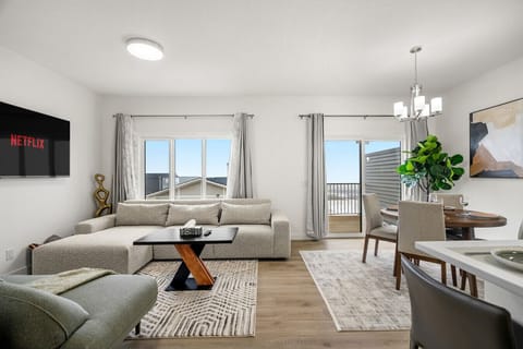 Open-concept living room with sectional sofa, dining area, and scenic balcony views