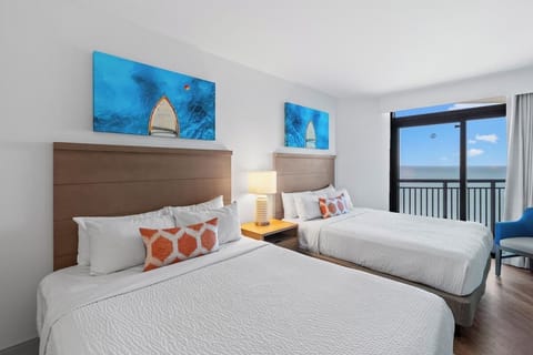 Unwind in crisp beds with balcony breezes beyond.