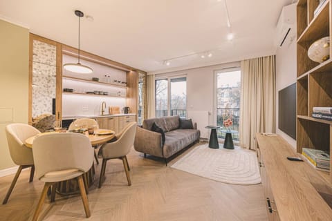 Spacious living room with panoramic windows, natural light, and cozy design – the heart of Camelia apartment in Bydgoszcz center.