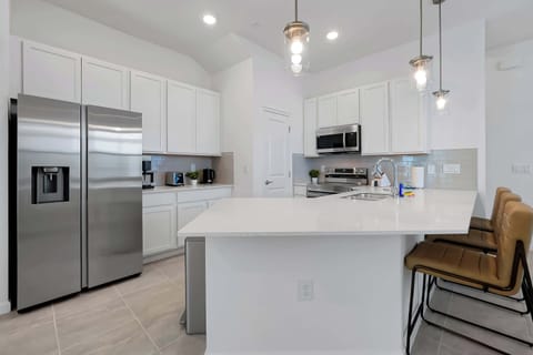 A fully equipped modern kitchen featuring stainless steel appliances and breakfast bar seating.