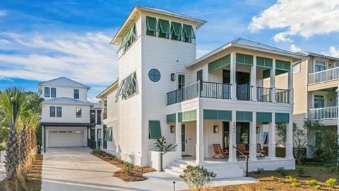 Magnolia Mooring — a light-filled coastal retreat with classic white siding, breezy double porches, and signature green shutters, perfectly positioned in the heart of Kiva Dunes just a short walk to the beach.