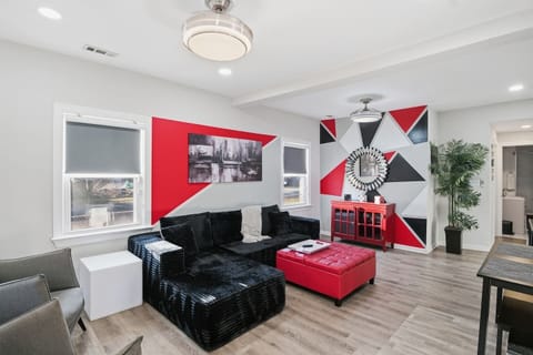 Step into a welcoming living room with sleek flooring and modern red‑and‑black décor. Plush seating, a spacious sectional, and a large ottoman make it ideal for relaxing. With a Roku TV and a hutch full of games, it’s built for cozy nights in.