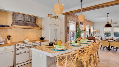 Your spacious kitchen flows seamlessly into the dining area, where warm wood tones and wicker seating create the perfect spot for memorable meals.