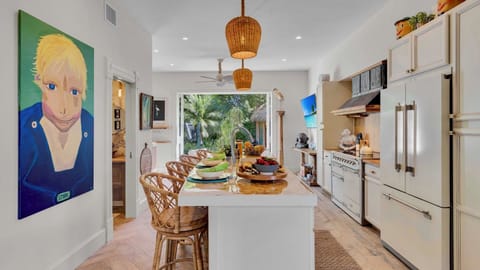 Your gourmet kitchen features a spacious island, premium appliances, and tropical garden views through large windows.