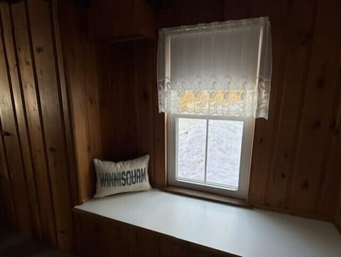 Cozy window nook with warm wood paneling where you can curl up with morning coffee and watch snow fall outside.