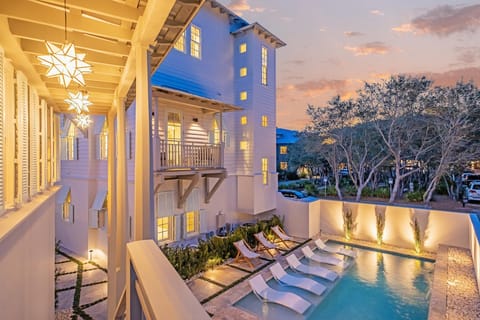 Luxury coastal home features pool, covered porches, and stunning sunset backdrop for memorable beach getaway.