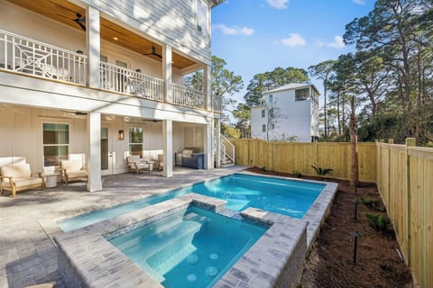 Your private backyard oasis awaits with a sparkling pool and hot tub, perfect for relaxing after beach days on the covered patio.