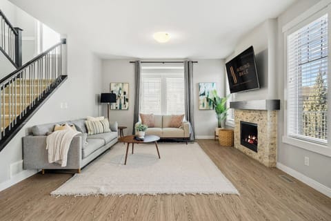 Main floor living room with a Smart TV, gas-lit fireplace, cozy seating options & walkout access to the backyard.