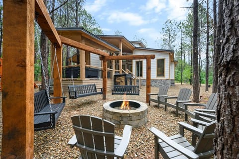 An inviting fire pit lounge with Adirondack chairs and swings, perfectly positioned beside the cabin.