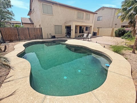 Backyard swimming pool with patio and two-story house