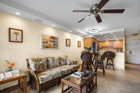 Your tropical-themed living space flows seamlessly into the kitchen, featuring wicker furnishings and coastal artwork that perfectly capture the island vibe you're seeking.