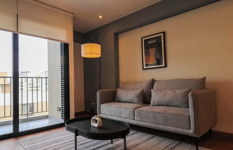 Bright living room with cozy sofa, natural light, and balcony access.
