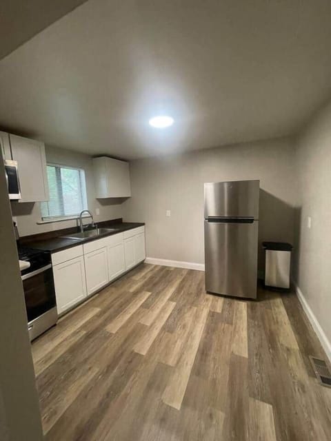 This bright and spacious kitchen includes a sink, ample cabinets, a refrigerator, oven, and stove.