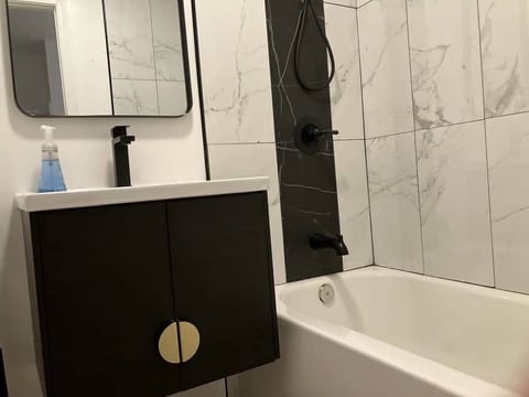 This cozy bathroom includes a bathtub perfect for a soothing soak, a modern sink, and a mirror for all your grooming needs.