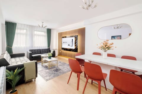 Living Room | Elevated luxury awaits in the living room, featuring a beautifully decorated space with a 70 inch smart TV, an open plan fully equipped kitchen, and a dining table seating up to 8 guests, perfect for sharing meals in comfort.