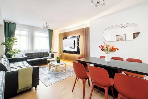 Living Room | Elevated luxury awaits in the living room, featuring a beautifully decorated space with a 75 inch smart TV, an open plan fully equipped kitchen, and a dining table seating up to 8 guests, perfect for sharing meals in comfort.