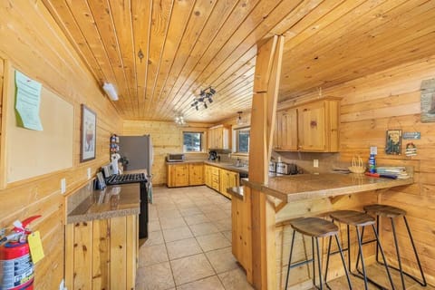 Warm cabin kitchen with knotty pine, breakfast bar, and modern appliances.