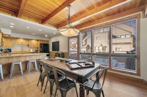 Gather around this stunning dining table where rustic wood meets modern comfort under dramatic exposed beams.