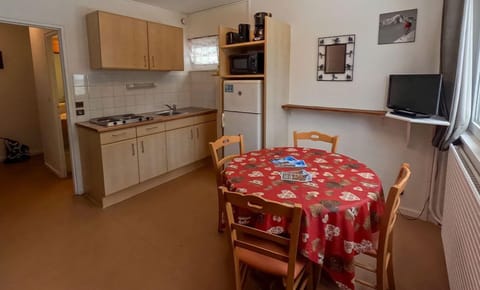 The cozy kitchenette features a red tablecloth and a well-equipped space for meal preparation, bringing a warm atmosphere to the apartment.