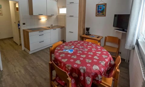 A bright and modern kitchen setup invites you to prepare meals, with a welcoming dining table at the center, fostering togetherness in a warm, mountain-inspired ambiance.