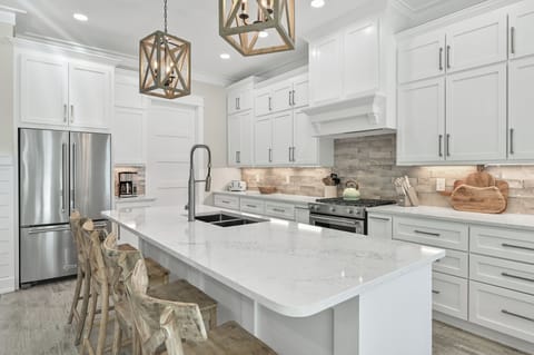 Chef’s kitchen featuring white cabinetry, a large island, and subway tile backsplash.