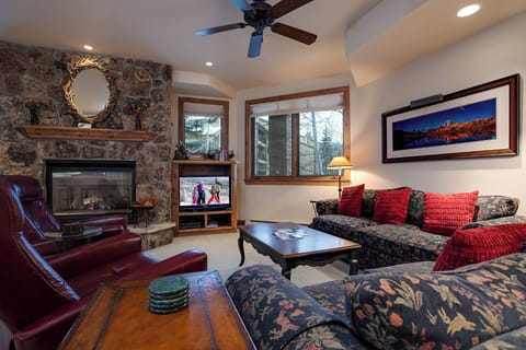 Curl up by your crackling stone fireplace in this cozy living room, where soft sofas and warm lighting create the perfect mountain retreat atmosphere.