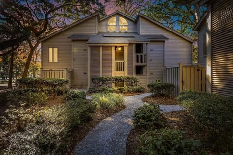 Charming property exterior featuring warm lighting and landscaped grounds at dusk.