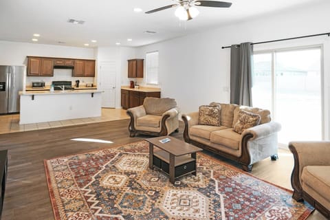 Open living room with sofas, rug, and kitchen in background