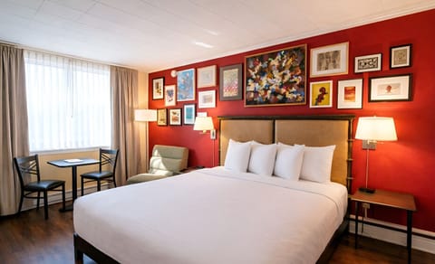 A bright bedroom with one king bed, crisp white linens, and a convenient in-room kitchenette.