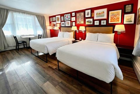 A bright bedroom with two full sized beds, crisp white linens, and a convenient in-room kitchenette.