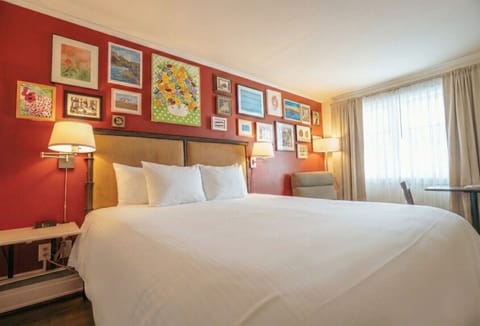 A bright bedroom with one king bed, crisp white linens, and a convenient in-room kitchenette.