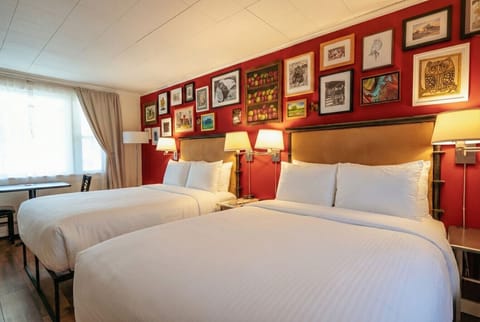 A bright bedroom with two full sized beds, crisp white linens, and a convenient in-room kitchenette.