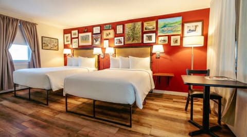 A bright bedroom with two full sized beds, crisp white linens, and a convenient in-room kitchenette.