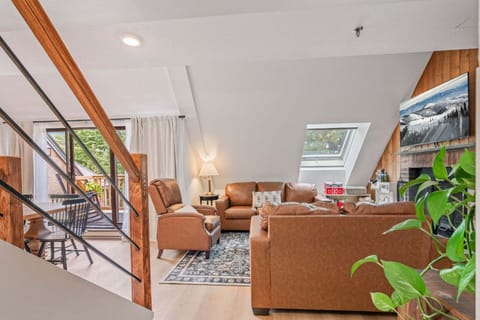 Pale wood floors, crisp white walls, and a vaulted ceiling give the two-level living space its clean, upscale mountain feel.