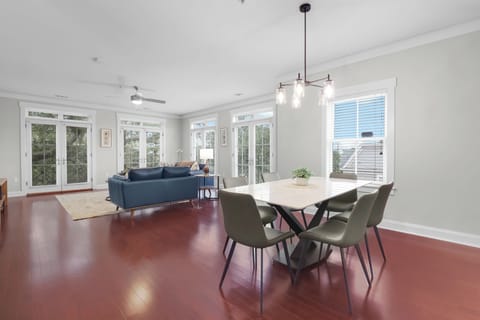 Airy and inviting living-dining space framed by tall windows and contemporary finishes.