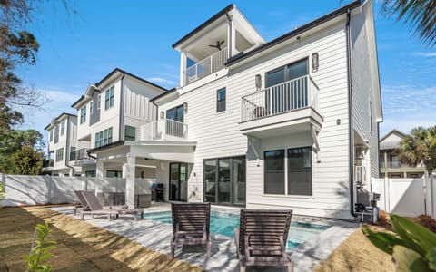 Modern multi-story vacation home with private pool, outdoor lounging area, and tropical landscaping in a peaceful neighborhood setting.
