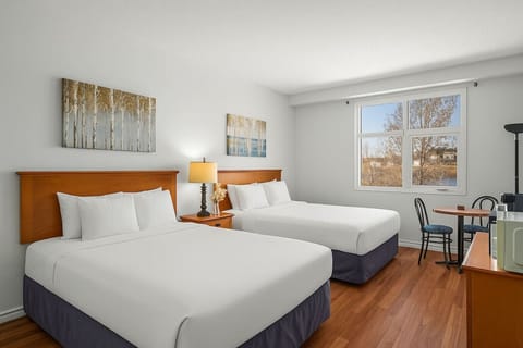 A cozy studio featuring two queen beds and a dining area for two, perfect for a comfortable stay.