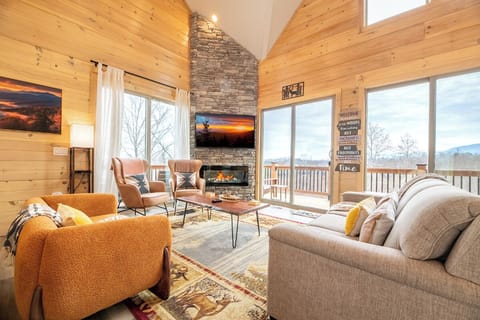 Unwind in your mountain retreat's cozy living room, where warm wood walls and a stone fireplace create perfect moments for relaxation.