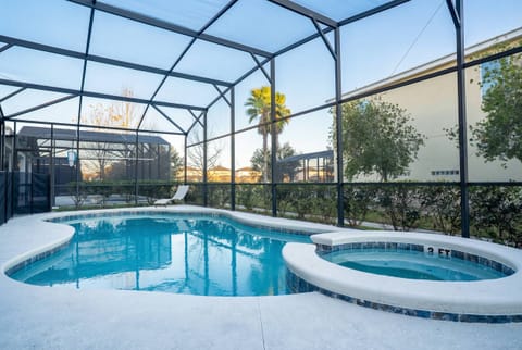 Relax in a private screened pool area with a sparkling pool, raised spa, and peaceful green views. Natural light, a lounge chair, and the airy enclosure create a calm spot to unwind after fun days in Orlando.