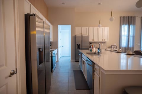 Experience a bright kitchen bathed in natural light with sleek stainless steel appliances and pristine white cabinetry. The spacious countertop invites cooking and togetherness, making it a perfect spot for shared moments.