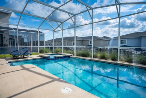 Relax in a private screened pool area with sparkling water, a raised spa, lounge chairs, open sky views, and peaceful surroundings, creating a refreshing space for family vacation moments.