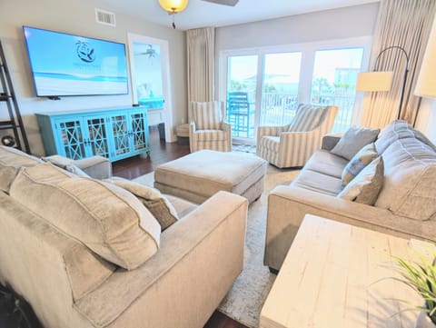 Cozy coastal family room with balcony and palm views and large smart TV.