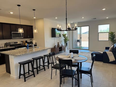 Open kitchen and dining area with island, stools, table, and TV