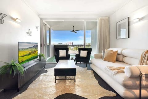 Living Room: Bright open-plan living area with balcony access, featuring sleek furnishings, a king-size sofa bed, dimmable lighting, and sheer & blackout curtains for a relaxing stay.