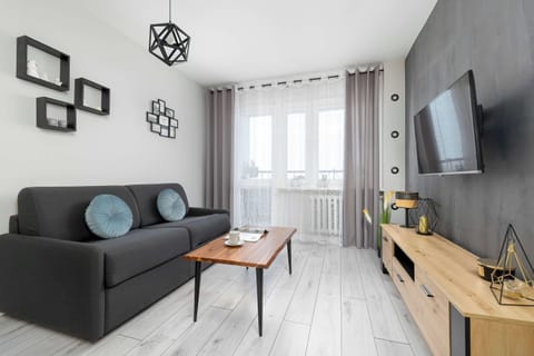 Stylish living room with a gray sofa, wooden TV unit, and modern wall décor.