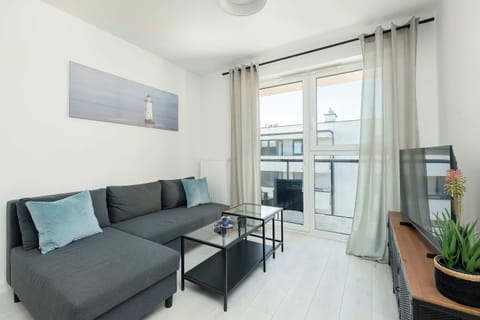 A modern living room with a grey sofa, coffee table, and plenty of natural light. Perfect for relaxing or socializing with friends and family.