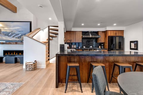 You'll love cooking and gathering in this stunning open kitchen with rich wood cabinetry, sleek black countertops, and bar seating.
