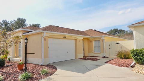 Charming beige villa with private garage and landscaped courtyard in a peaceful residential community.